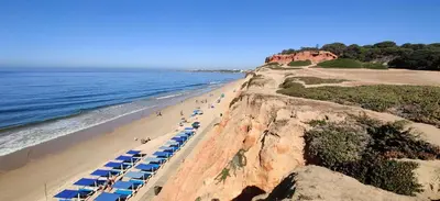 a beach with blue beach umbrellas and the ocean at Casal dos Machados - Vista Mar in Benfarras