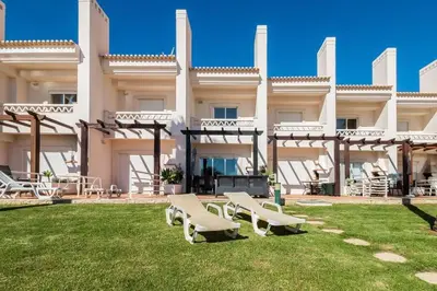 a large building with two benches in the yard at Fantastic Townhouse with Pool and Sea Views in Albufeira