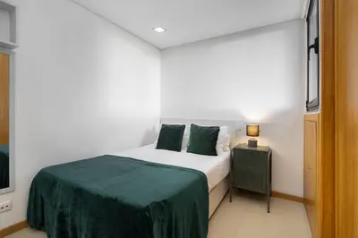a bedroom with a bed with a green blanket at Amazing Flat In Olhos de Água in Olhos de Água