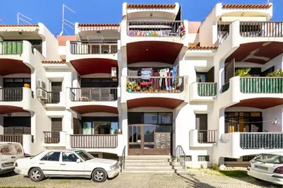 a white apartment building with cars parked in front of it at Amazing Flat In Olhos de Água in Olhos de Água