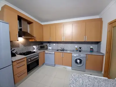 a kitchen with wooden cabinets and a washer and dryer at Apartamento Loft 39 by Sunnyway in Albufeira