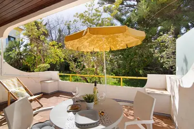 a patio with a table and a yellow umbrella at África Minha in Vilamoura