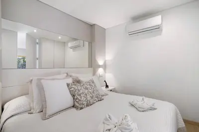 a white bedroom with a bed with white sheets and pillows at África Minha in Vilamoura