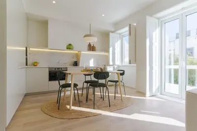 a white kitchen with a table and chairs at Modern & Bright Faro Mercado Apt 12 by Lisbeyond in Faro