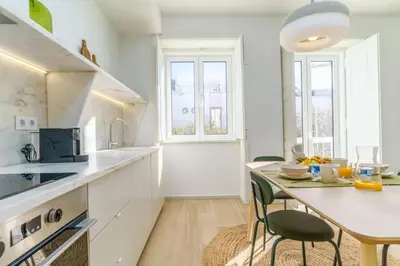 a white kitchen with a table and chairs at Modern & Bright Faro Mercado Apt 12 by Lisbeyond in Faro