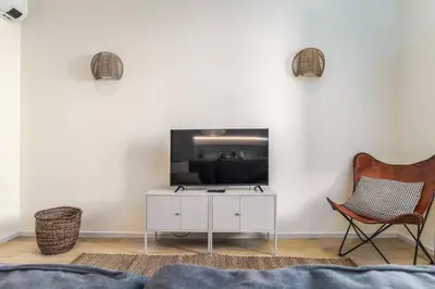 a living room with a tv and a chair at Modern & Cozy Faro Mercado Apt 11 by Lisbeyond in Faro
