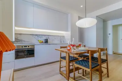 a kitchen with white cabinets and a wooden table and chairs at Modern & Cozy Faro Mercado Apt 11 by Lisbeyond in Faro