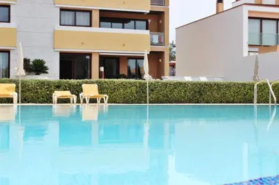 a swimming pool with chairs in front of a building at Monte Laguna Apartment in Quarteira