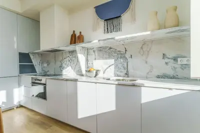 a kitchen with white cabinets and marble counter tops at Modern & Bright - Faro Mercado Apt 22 by Lisbeyond in Faro
