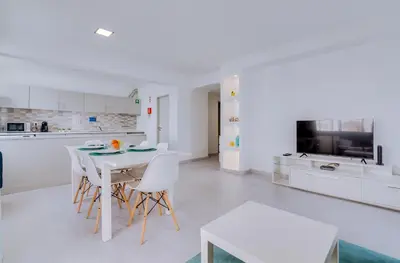 a white kitchen with a white table and chairs at AL - Apartamento Quarteira Avenida in Quarteira