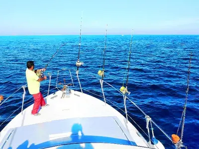 a man fishing on a boat in the ocean at Luxury Holiday Villa Pescadinha near Beach, Albufeira in Albufeira