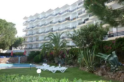 a hotel with two white benches in front of a building at Apartamentos Mar-Bel Sol in Vilamoura