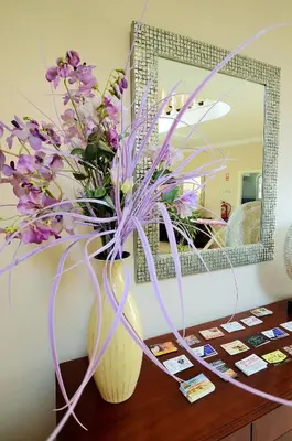 a vase of purple flowers on a table in front of a mirror at Suites & Beds DP Albufeira in Albufeira