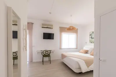 a white bedroom with a bed and a table at Faro Guest Apartments in Faro