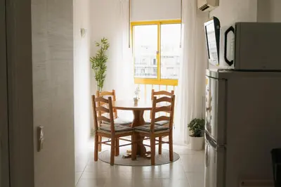 a table and chairs in a kitchen with a window at Happy House in Quarteira