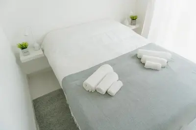 a white bed with two rolled towels on it at Happy House in Quarteira