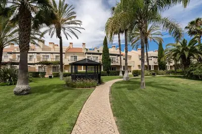 a large building with palm trees and a walkway at Palmyra by Intiholidays in Vilamoura