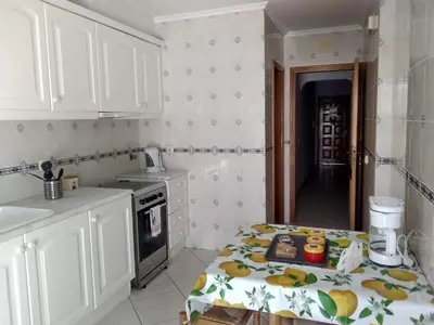a kitchen with white cabinets and a table in it at Apartamentos Monica in Quarteira