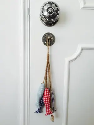 a clock on a white wall with a doll hanging on it at Quarteira Paul Harris Apartment in Quarteira