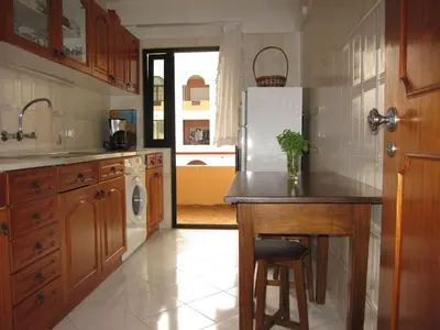 a kitchen with a counter and a refrigerator at Quarteira Paul Harris Apartment in Quarteira