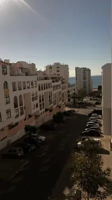 a city street with cars parked in a parking lot at Quarteira Paul Harris Apartment in Quarteira