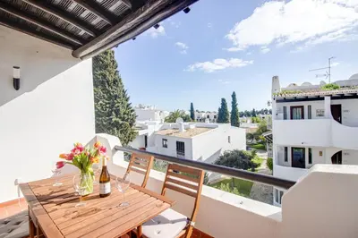 a balcony with a wooden table with flowers on it at Welcoming Oasis 500m Beach AC Wi-Fi Pool Balcony in Albufeira