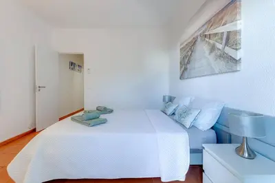 a bedroom with a white bed and a blue couch at VILA MAGNA - Apart renovado para 4 com piscina e Ar condicionado in Albufeira
