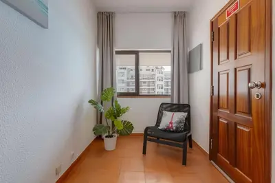a hallway with a black chair and a window at VILA MAGNA - Apart renovado para 4 com piscina e Ar condicionado in Albufeira
