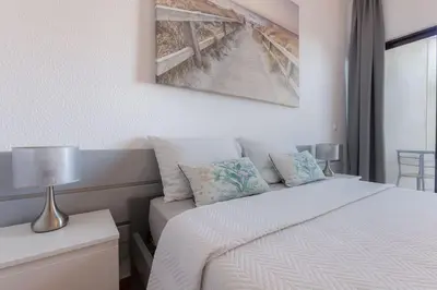 a white bedroom with a bed and a couch at VILA MAGNA - Apart renovado para 4 com piscina e Ar condicionado in Albufeira