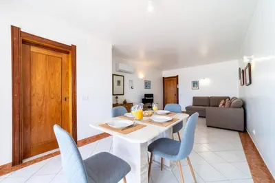 a dining room and living room with a table and chairs at Colibri by HelloVacations in Albufeira