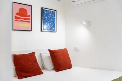 a white bed with two red pillows in a room at Tasteful 1 BDR Flat W/Balcony & Pool by LovelyStay in Quarteira