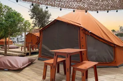 an orange tent with a table and two stools at Glamping Camp Faro in Faro