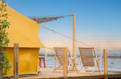 two chairs and a tent on a deck at Glamping Camp Faro in Faro
