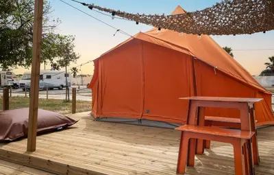 an orange tent on a wooden deck with a stool at Glamping Camp Faro in Faro