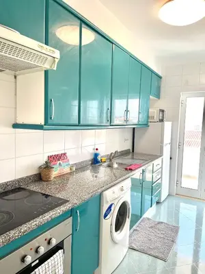 a kitchen with blue cabinets and a washing machine at Flat Luxuoso Praia da Oura in Albufeira