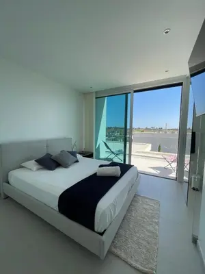 a bedroom with a large bed and a large window at Casa Papoila in Albufeira