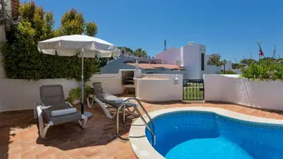 a swimming pool with chairs and a house at Villa Rosa in Vale do Lobo