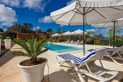 a pool with chairs and an umbrella and a palm tree at Design Chalet in Albufeira With Private Pool in Albufeira
