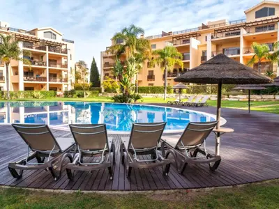 a deck with chairs and an umbrella next to a swimming pool at Apartment Triplex Vilamoura VIP Properties by Interhome in Vilamoura