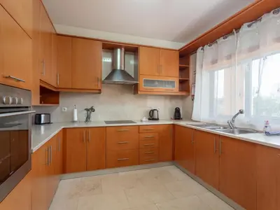 a kitchen with wooden cabinets and a sink and a window at Apartment Triplex Vilamoura VIP Properties by Interhome in Vilamoura