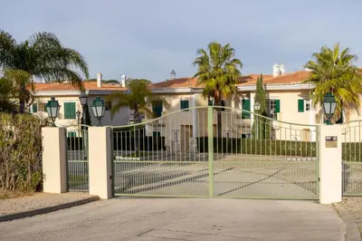 a gate in front of a house with palm trees at Quinta do Lago Golfside Retreat in Quinta do Lago