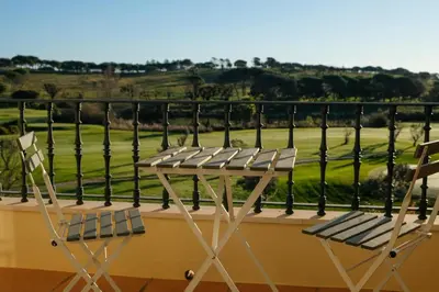 two chairs and a table on a balcony with a golf course at Quinta do Lago Golfside Retreat in Quinta do Lago