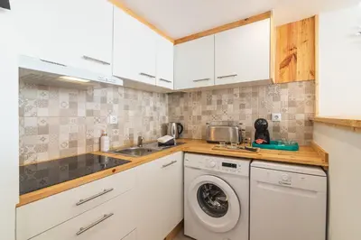 a kitchen with white cabinets and a washer and dryer at Flat with Pool T2 Duplex Montechoro in Albufeira