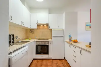 a white kitchen with white cabinets and a sink at Apartamento Ivone by Sunnyway in Albufeira
