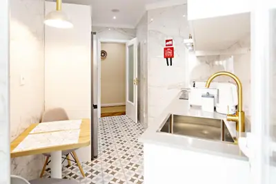 a white kitchen with a sink and a table at Blue Peacock in Faro