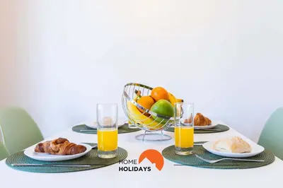 a table with plates of food and a basket of fruit at #152 T1 Falésia by Home Holidays in Albufeira