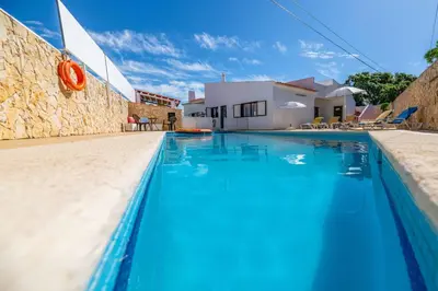 a blue swimming pool in front of a house at Villa Mar do Estrela in Galé