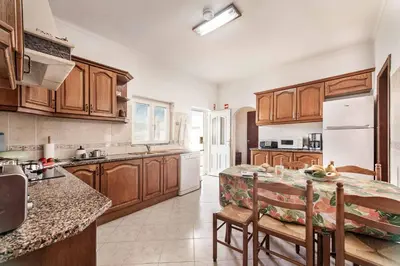 a kitchen with wooden cabinets and a table with chairs at Villa Bento Dios in Galé
