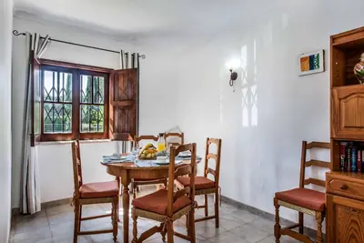 a dining room with a table and chairs and a window at Villa Mendes in Vilamoura