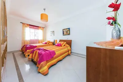 two beds in a large room with flowers in a room at Villa Encosta do Sol in Albufeira